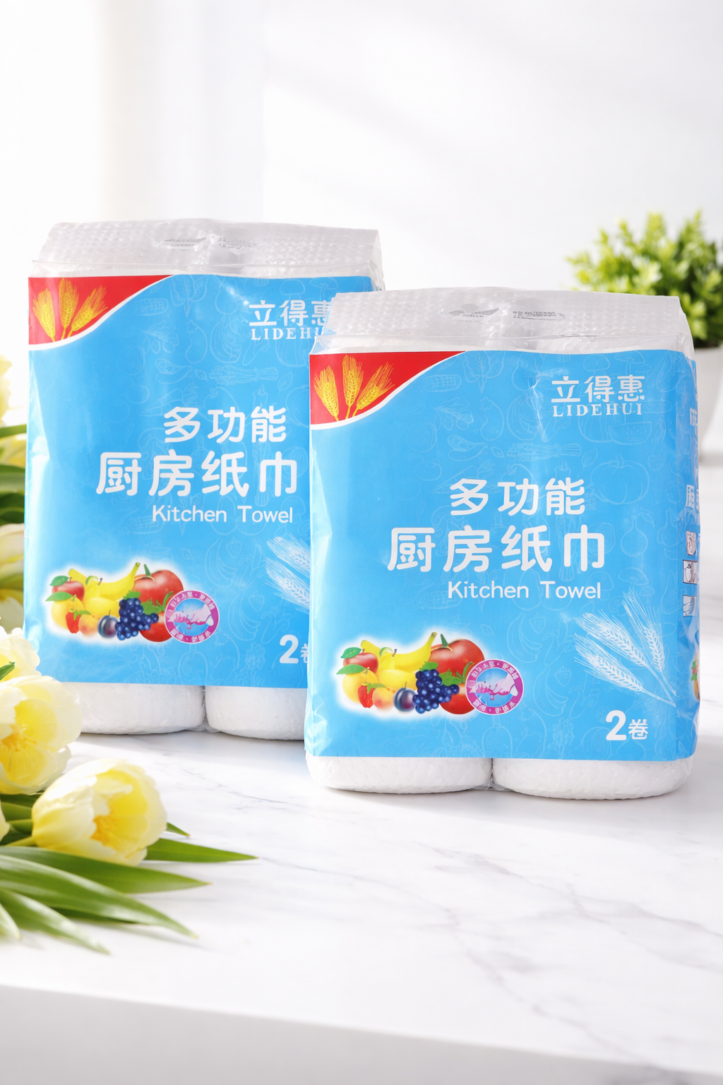 Kitchen Towel pack on marble surface, featuring blue packaging and vibrant fruit illustrations, two rolls per pack.