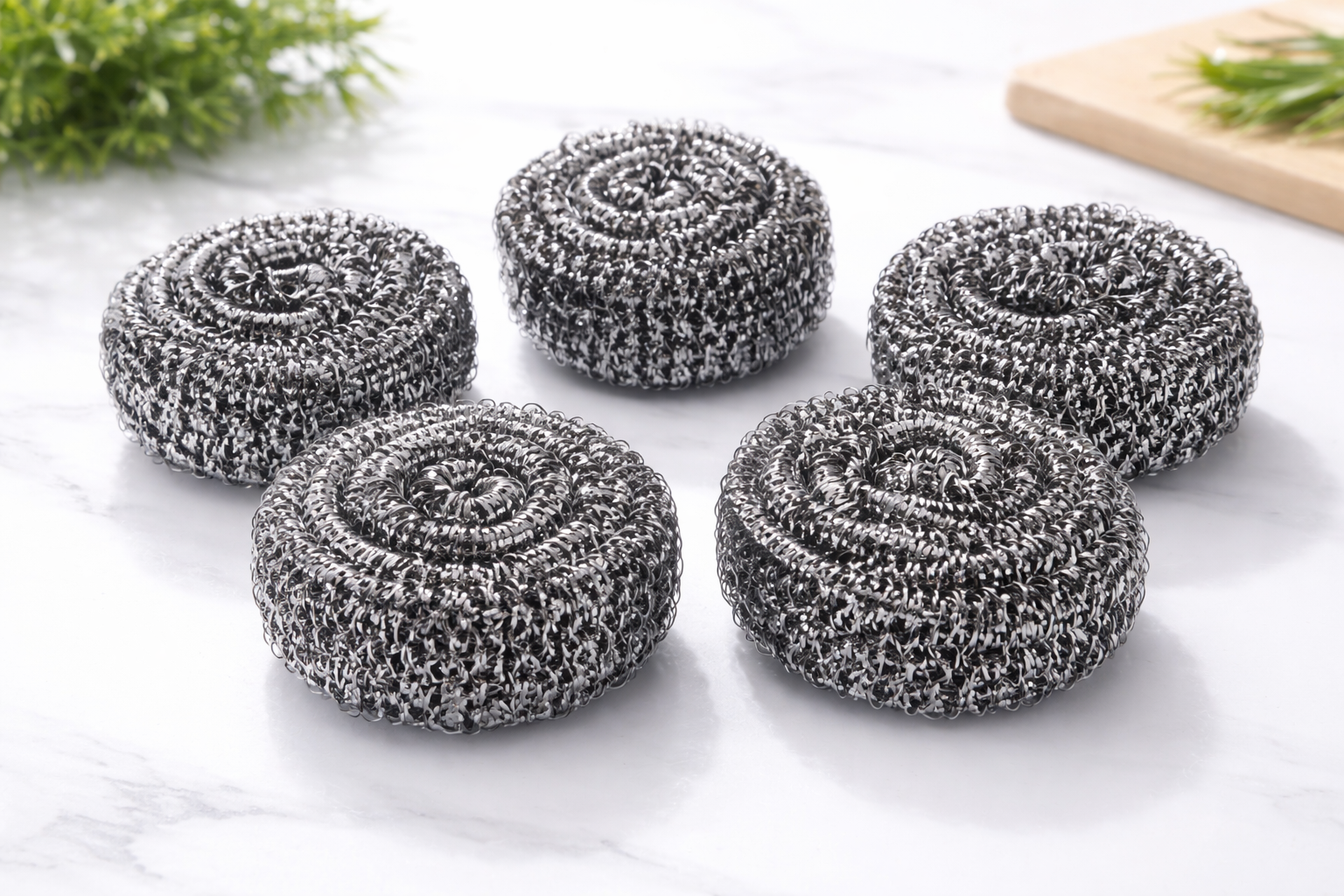 Five silver stainless steel brush balls on white marble surface, crafted with tightly coiled wire.